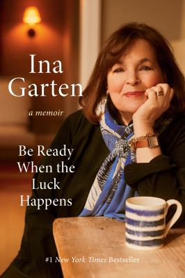 Book Cover:Ina Garten's Be Ready When the Luck Happens Book Cover, Ina sitting at a wooden table with a blue coffee mug