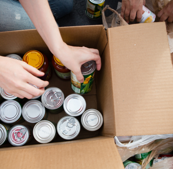 Hands packaging canned goods in a box